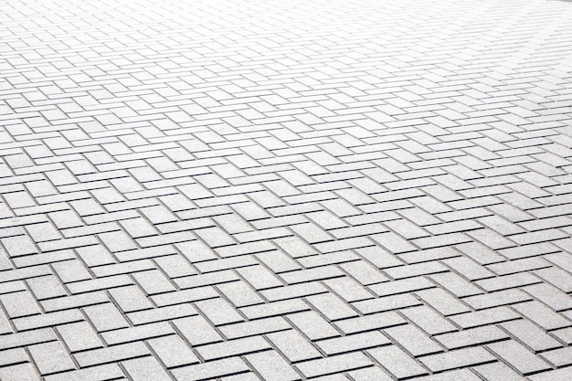 Texture of gray patterned paving tiles on the ground of street, perspective view.