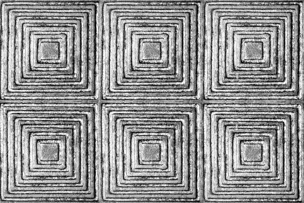 The texture of a metal surface with a pattern in the form of squares and rhombuses in black and white.