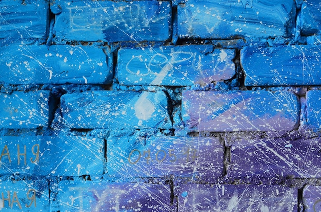 The texture of the old brick wall painted in blue and purple colors with carelessly spaced white drops and splashes that visualize the stars in outer space