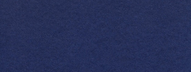 Texture of old navy blue color paper background macro Structure of a vintage craft dark denim cardboard