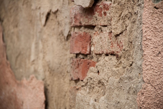 Texture of an old ragged wall Background of old bricks and cracks in plaster Yellow and brown tones