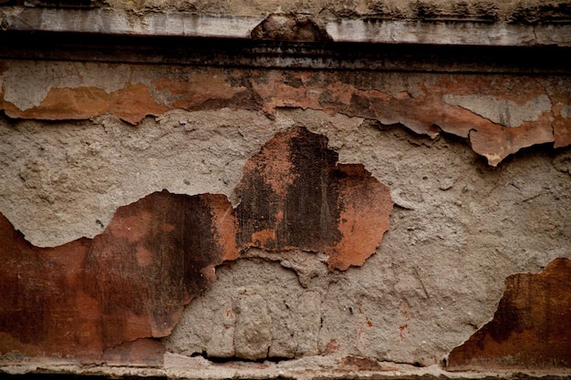 Texture of an old ragged wall Background of old bricks and cracks in plaster Yellow and brown tones