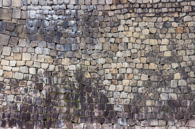 Texture of old stacked stone wall have grass along the rock