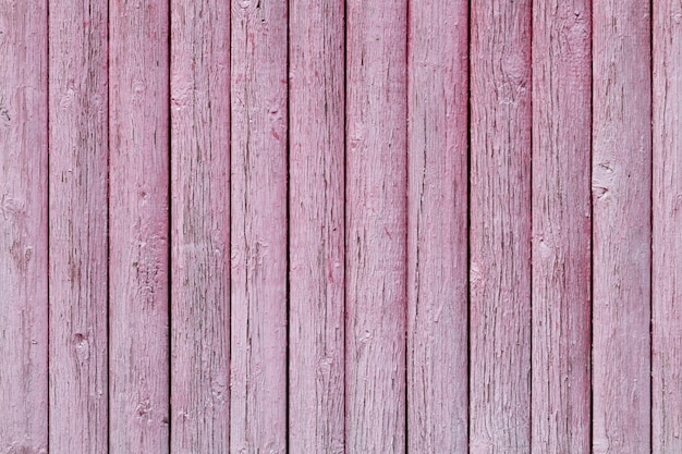 Texture old wooden fence with peeled pink paint