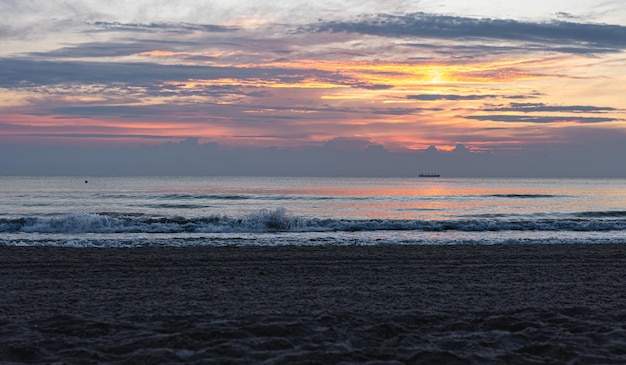 Texture sea waves at sunset with pink clouds