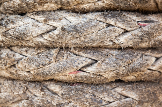 The texture of the ship's thick old rope twisted in several rows horizontally closeup