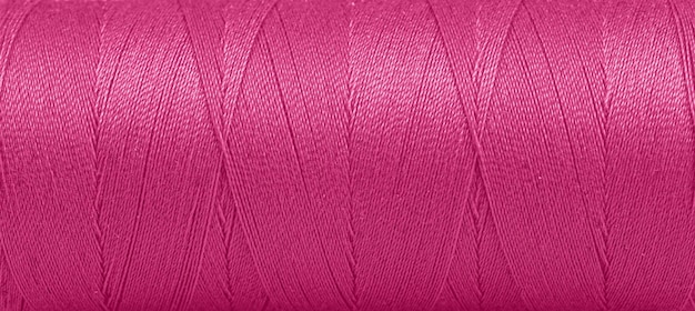 Texture of threads in a spool of pink color on a white background