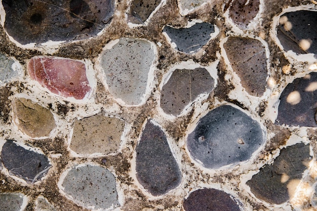 Texture of uneven stones The old wall Bright sunlight and deep shadows Abstract background