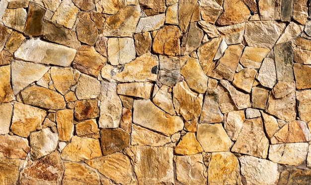 Texture of a varnished stone garden wall with orange and yellow tones Natural lighting Construction material