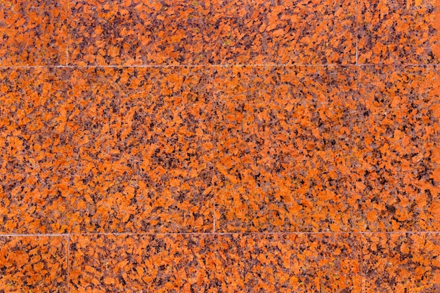 Texture of the wall with facing slabs of red, spotted, decorative, polished marble