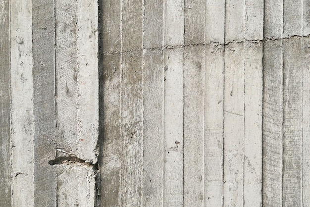 Texture of wooden formwork stamped on a raw concrete wall as background  