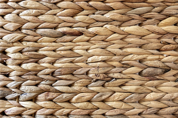 Texture of woven beige straw, background of braids from the plant stem close-up.