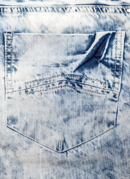 Textured back pocket of light blue jeans Close up