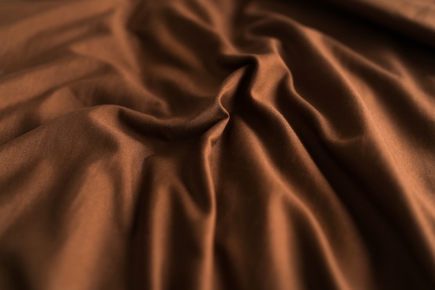 Textured background of brown plaid fabric with folds. High quality photo