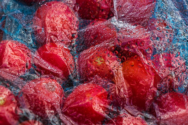 Textured background of freshly picked tomatoes under glass or film with water drops