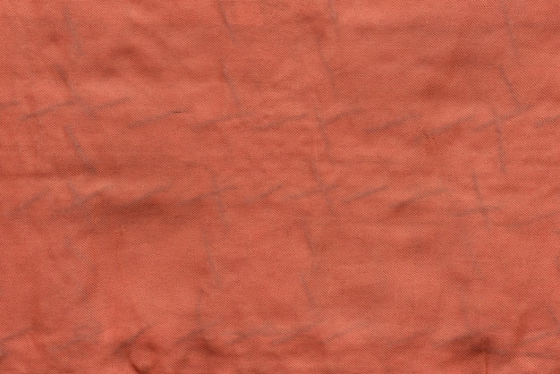 The textured background of old fabric or textile material of red color