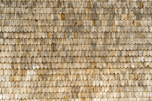 Textured background of wooden tiles on the roof of an old house