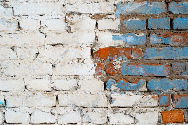 Textured grunge background. Brick wall with white and blue paint outdoors. Old, cracked horizontal brickwork with copy space for text.