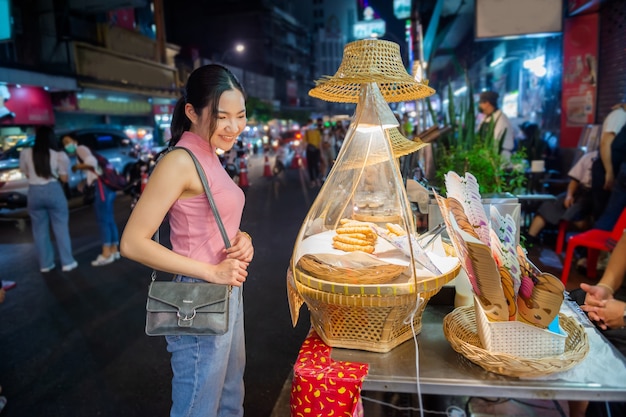 Thai-Chinese tourists stroll around and sample street food at Yaowarat Road, Chinatown, Bangkok