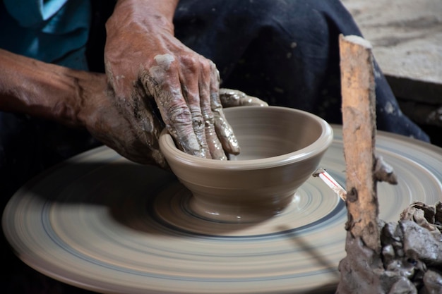 Thai craftsmanship technician or professional potter use machine working sculpture handmade pottery and handicraft earthenware for show sale at Koh Kret island in Pak Kret city at Nonthaburi Thailand