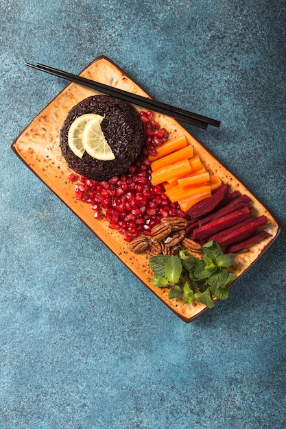 Thai diet food, Black Rice cooked with raw carrot, beetroot, pecan nuts, pomegranate and mint. Healthy vegan bowl. Top view with copy space.