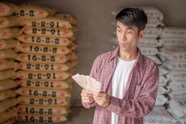 A Thai farmer holds banknotes with wow face at a fertilizer shop