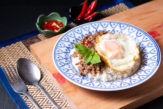 Thai Food concept Khao pad krapow rice and minced beef Thai holy basil stirfry with fried egg in thai style ceramic plate with copy space