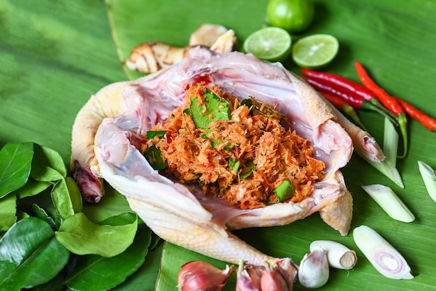 Thai food cooking with fresh chicken vegetables herbs and spices ingredients on banana leaf background raw chicken with lemon lime shallot garlic galangal lemon grass and chili