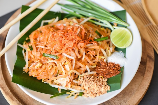 Thai food fried noodle Thai style with prawns bean sprout and garnish peanuts chili powder sugar lemon lime, Stir-fry noodle Pad Thai on plate served on the dining table food - top view