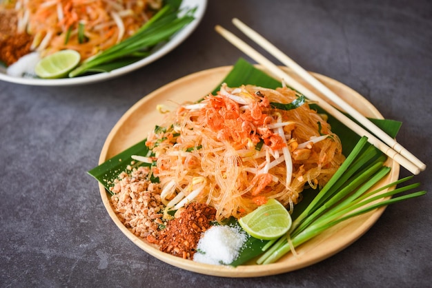 Thai food fried noodle Thai style with prawns bean sprout and garnish peanuts chili powder sugar lemon lime, Stir-fry noodle Pad Thai on plate served on the dining table food - top view