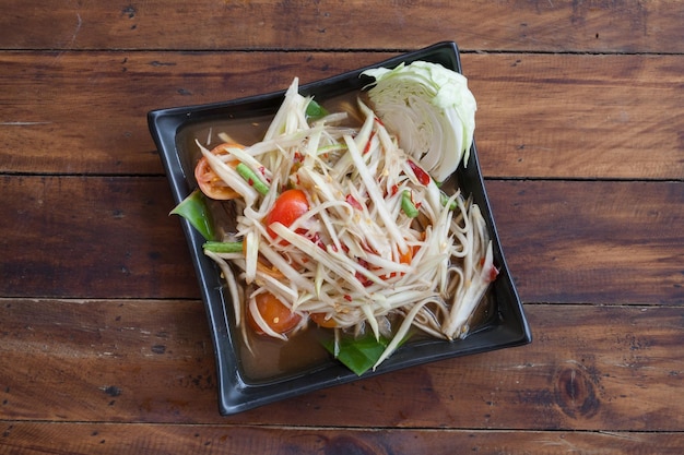 Thai food Spicy papaya salad on wooden table top view.