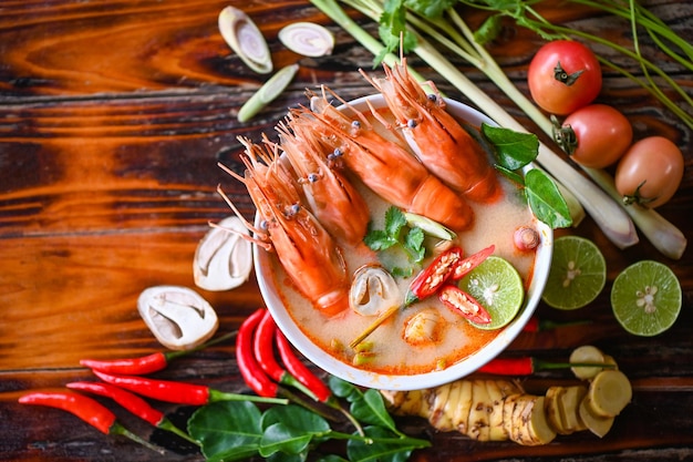 Thai Food Tom Yum Kung Hot and sour spicy shrimps prawns soup curry lemon lime galangal red chili straw mushroom on table food Shrimp soup on seafood soup bowl with thai herb and spices