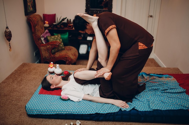 Thai man making classical thai massage procedure to young woman at beauty spa salon