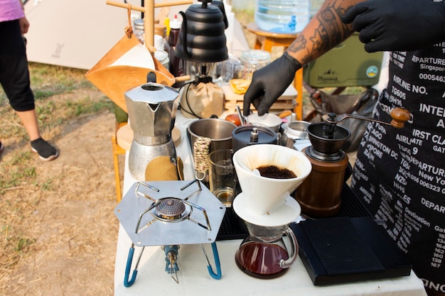 Thai men barista people use drip coffee maker or dripper made hot and iced coffee for sale beside irrigation canal at Bangbuathong city rural countryside on March 13 2021 in Nonthaburi Thailand