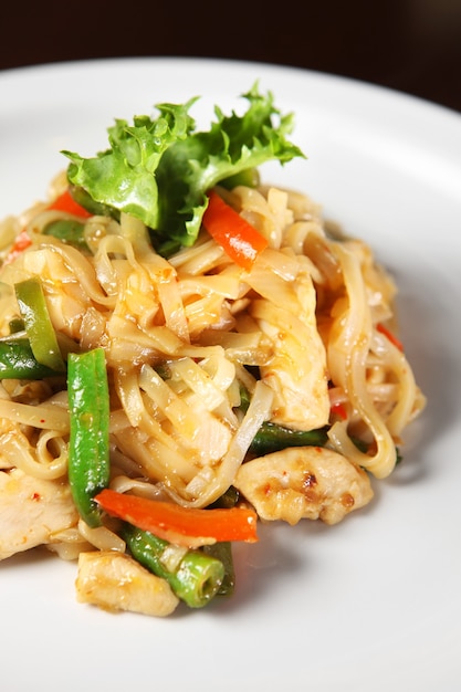 thai noodle with chicken and vegetables served on a white plate