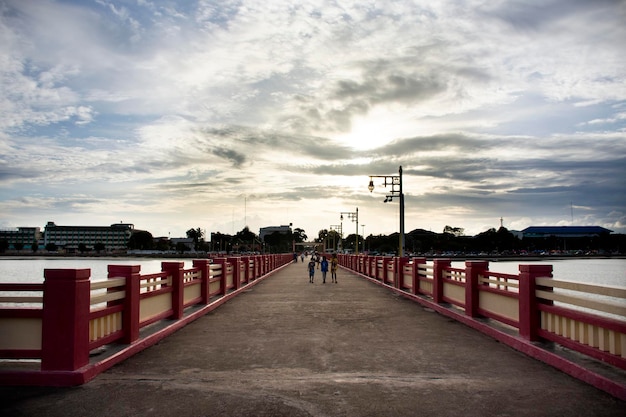 Thai people and foreign travelers travel visit rest relax and exercise playing sport on Saphan saranwithi red bridge sunset at Prachuap bay beach on September 6 2021 in Prachuap Khiri Khan Thailand