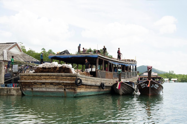 Thai people workers shipping product up and down from wooden ship and waiting passenger at Bang Rong Pier for go to Koh Yao Noi Harbour on June 6 2016 in Phuket Thailand