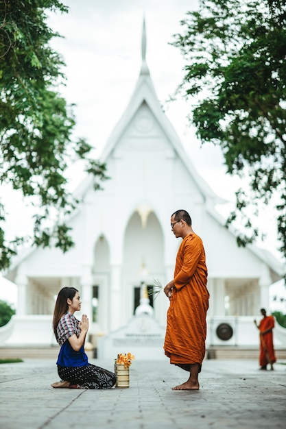 Thai woman with traditional dress praying with monk