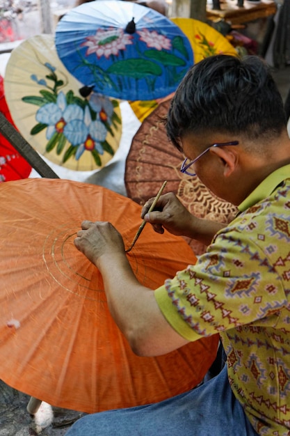 Thailand, Bangkok, a Thai artist decorating an umbrella in an umbrella factory