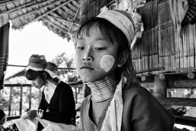 Photo thailand, chang mai, karen long neck hill tribe village (kayan lahwi), young girl and her mother in traditional costumes. women put brass rings on their neck when they are 5 or 6 years old and increas