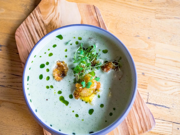 Thailand tradition green curry soup with shrimps prawns and coconut milk Green Curry in violet bowl on wooden background selective focus