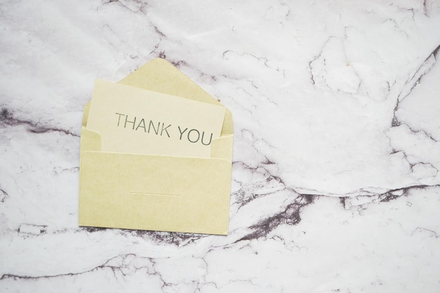 Thank you message and envelope on wooden table