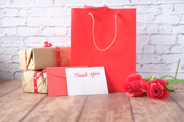 thank you message, gift box and envelope on wooden table