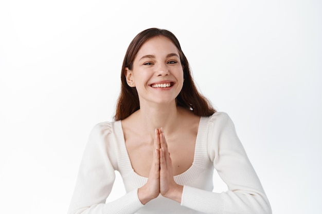 Thank you. Smiling attractive girl bowing with namaste gesture, express gratitude, thanking for help, greeting people with grateful emotion, standing over white background