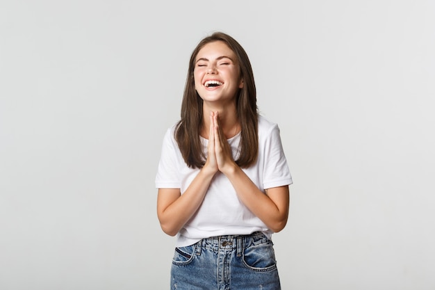 Thankful and relieved happy woman holding hands in pray, laughing with rejoice.