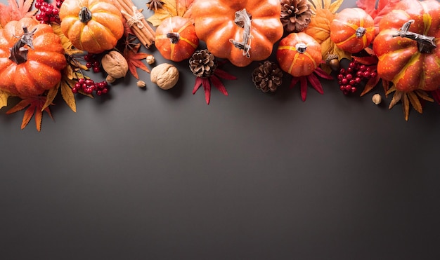 Thanksgiving and Autumn decoration concept made from autumn leaves and pumpkin on dark background Flat lay top view with copy space