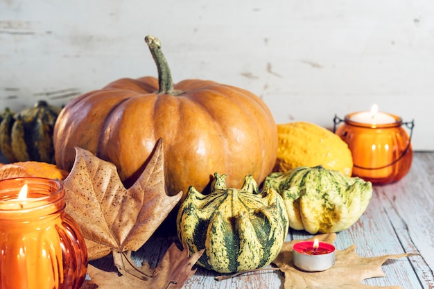 Photo thanksgiving background, composition with pumpkins, dry autumn leaves, candles on wooden background. autumn holiday, pumpkin harvest. seasonal vegetables.