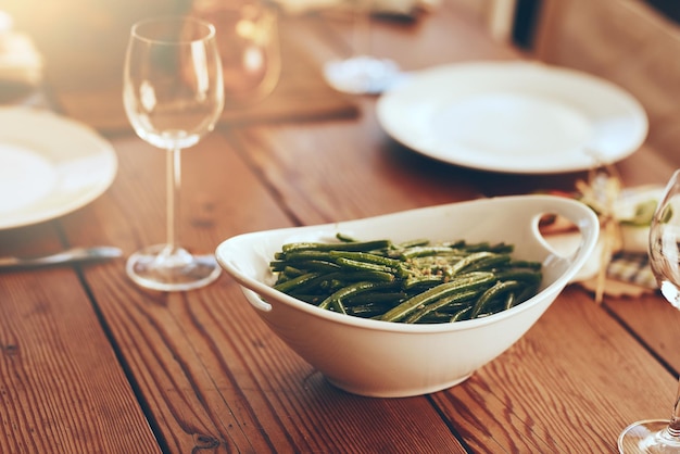 Thanksgiving green beans and food with a place setting on a dining room table for a celebration event Party dish and dinner with a bowl on a wooden surface in celebration or holiday tradition