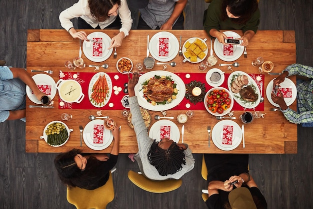 Thanksgiving overhead and friends sitting around a table for a food meal during a celebration event Family roast or nutrition with a man and woman group in the living room for a social gathering