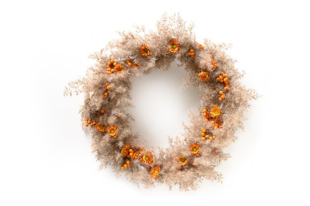 Thanksgiving wreath with orange flowers and dry natural materials isolated on white